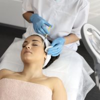 Cropped view of the young woman attending beautician, having anti-aging injection at her face. Cosmetology and skin care concept